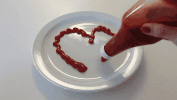 ketchup squirting out in a heart design on a plate