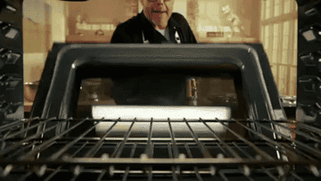 A man places some food stuff in the oven to get cooked.