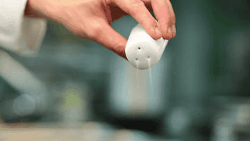 hand sprinkling a salt shaker