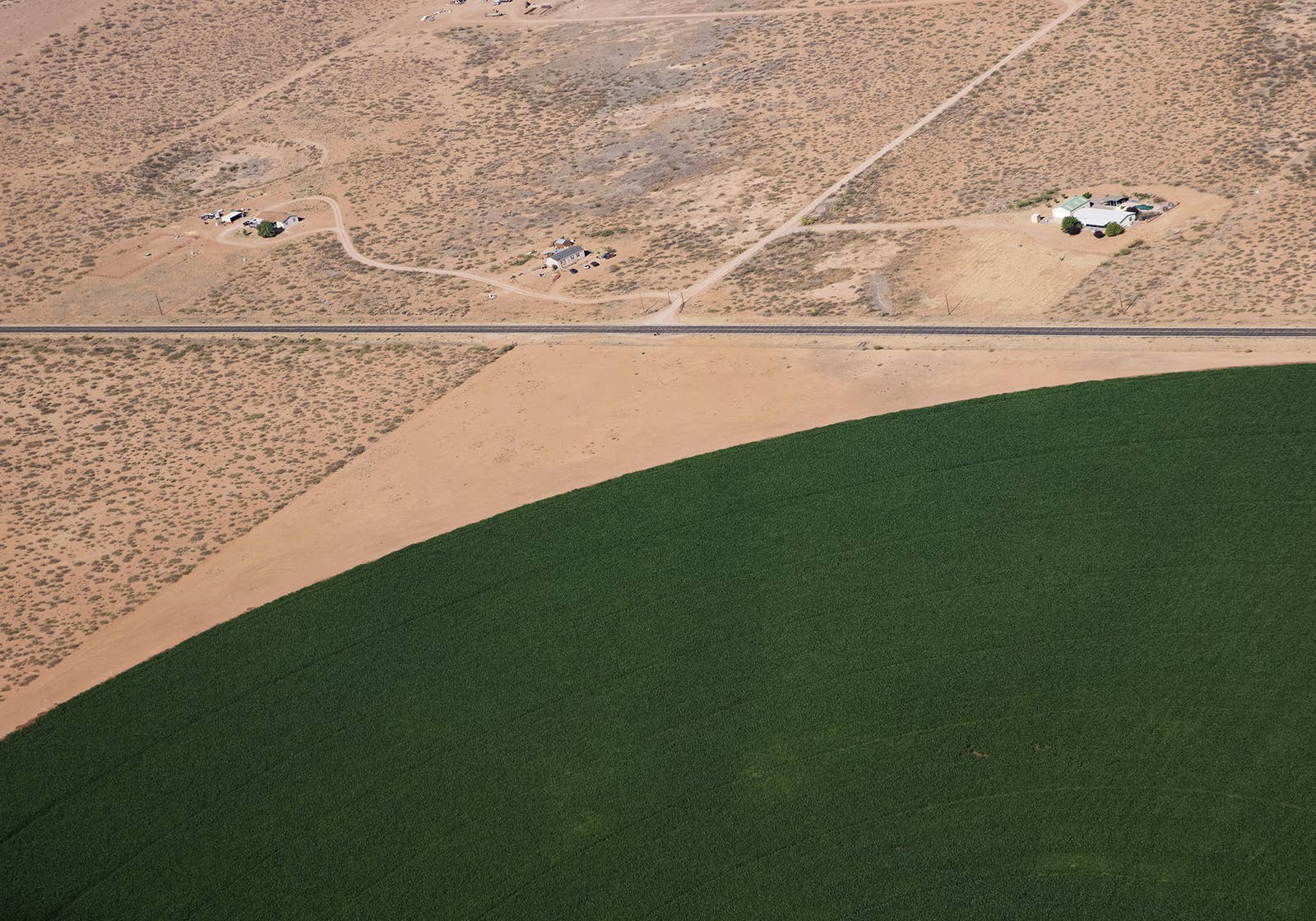 An irrigation circle green with vegetation edges up on a dry desert landscape