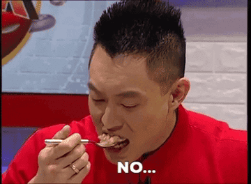 A man tasting a food and reacting in disgust.