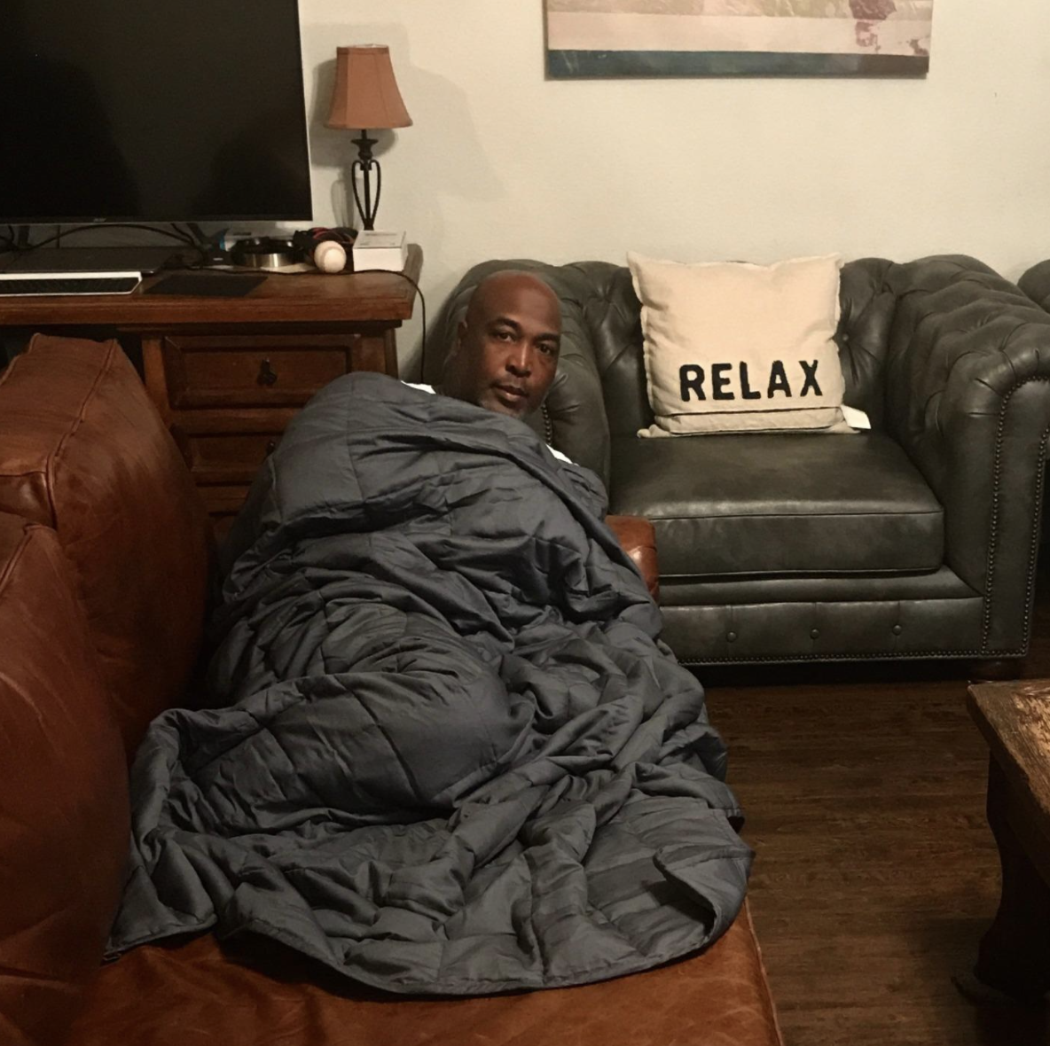 a reviewer photo of a person laying on a couch with the blanket over their body