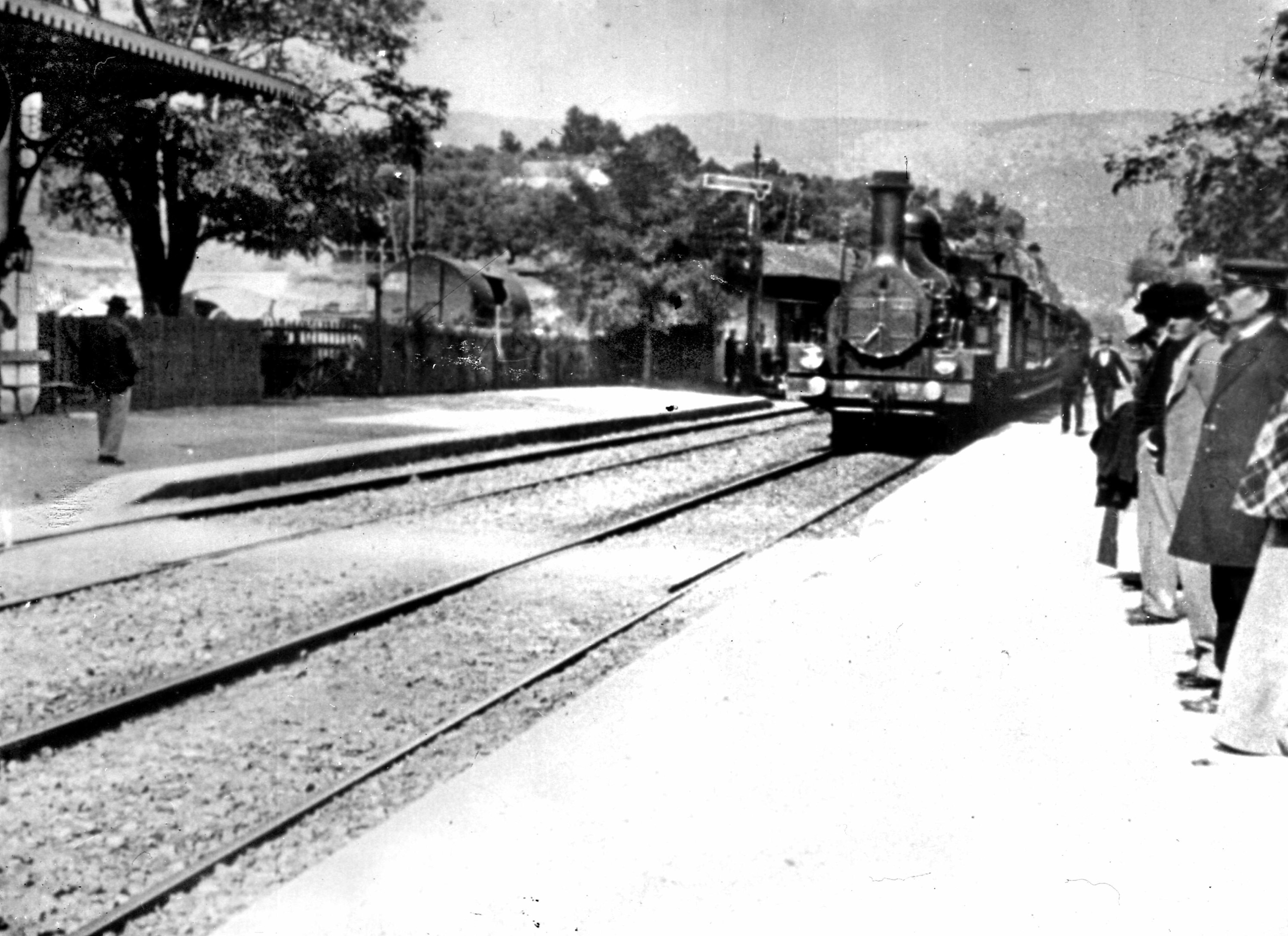 A black-and-white image of a train pulling into a station circa 1895