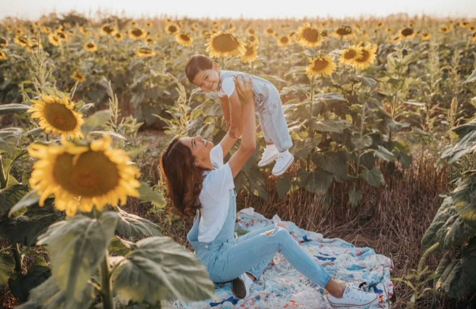 Nydia holding up her son in a sunflower field