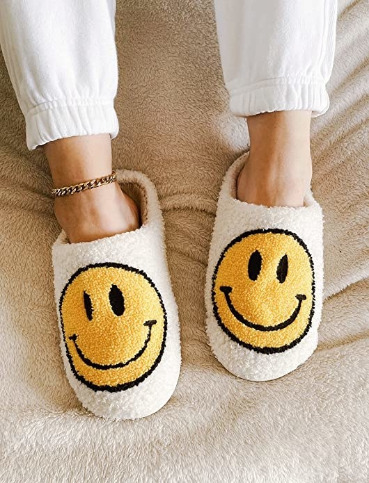 A person wearing the happy face slippers and an anklet