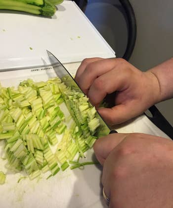 A reviewer using the chef's knife to cut cucumber finely