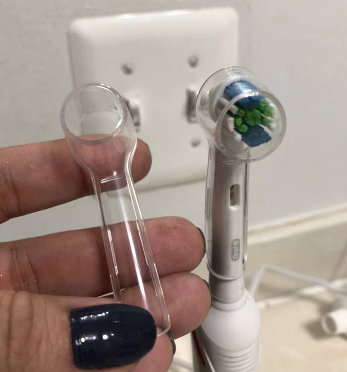 reviewer holding one of the toothbrush caps next to their toothbrush with a cap on it