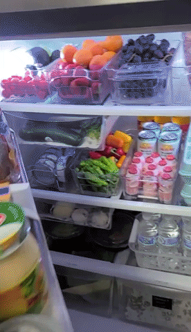 A gif of a fridge neatly organized with the clear bins