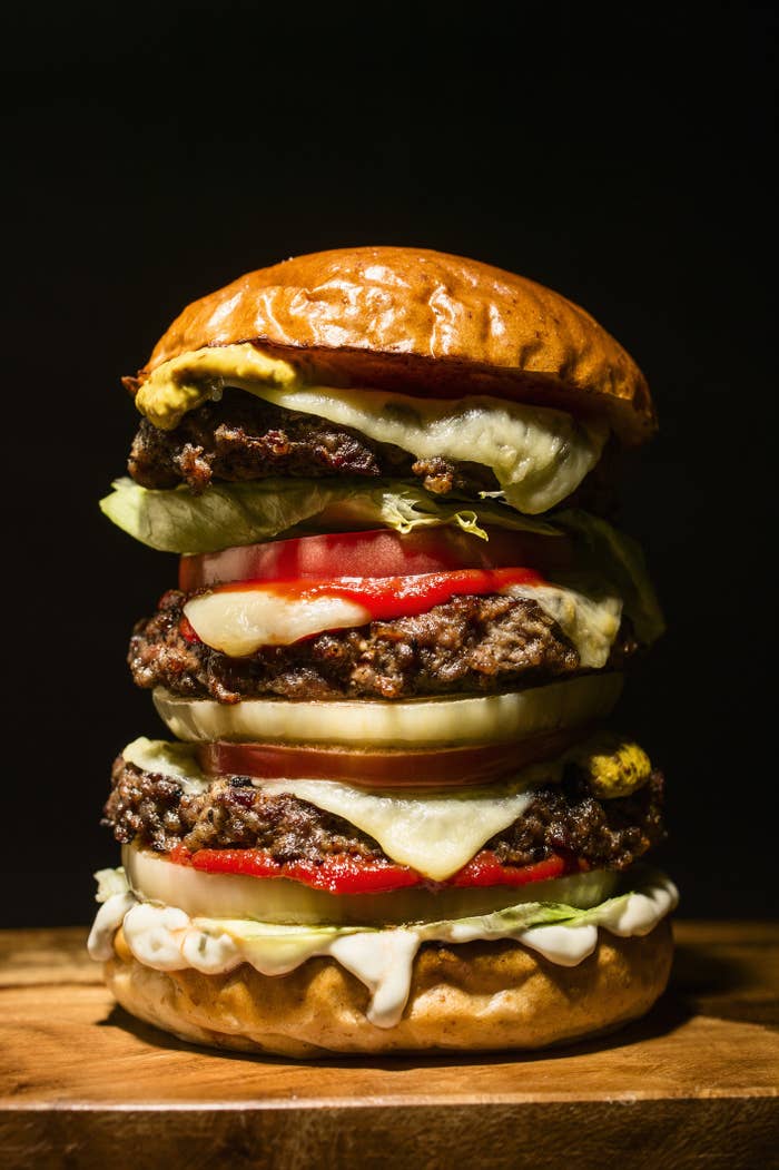A tall burger with three beef patties