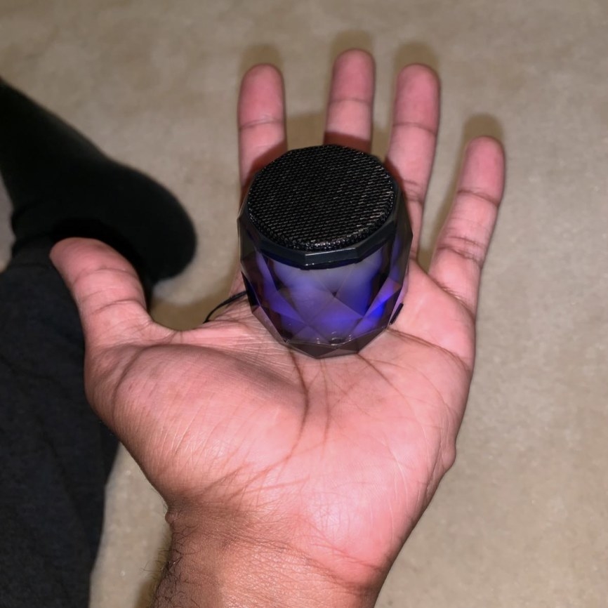 reviewer holding the mini bluetooth speaker in their hand