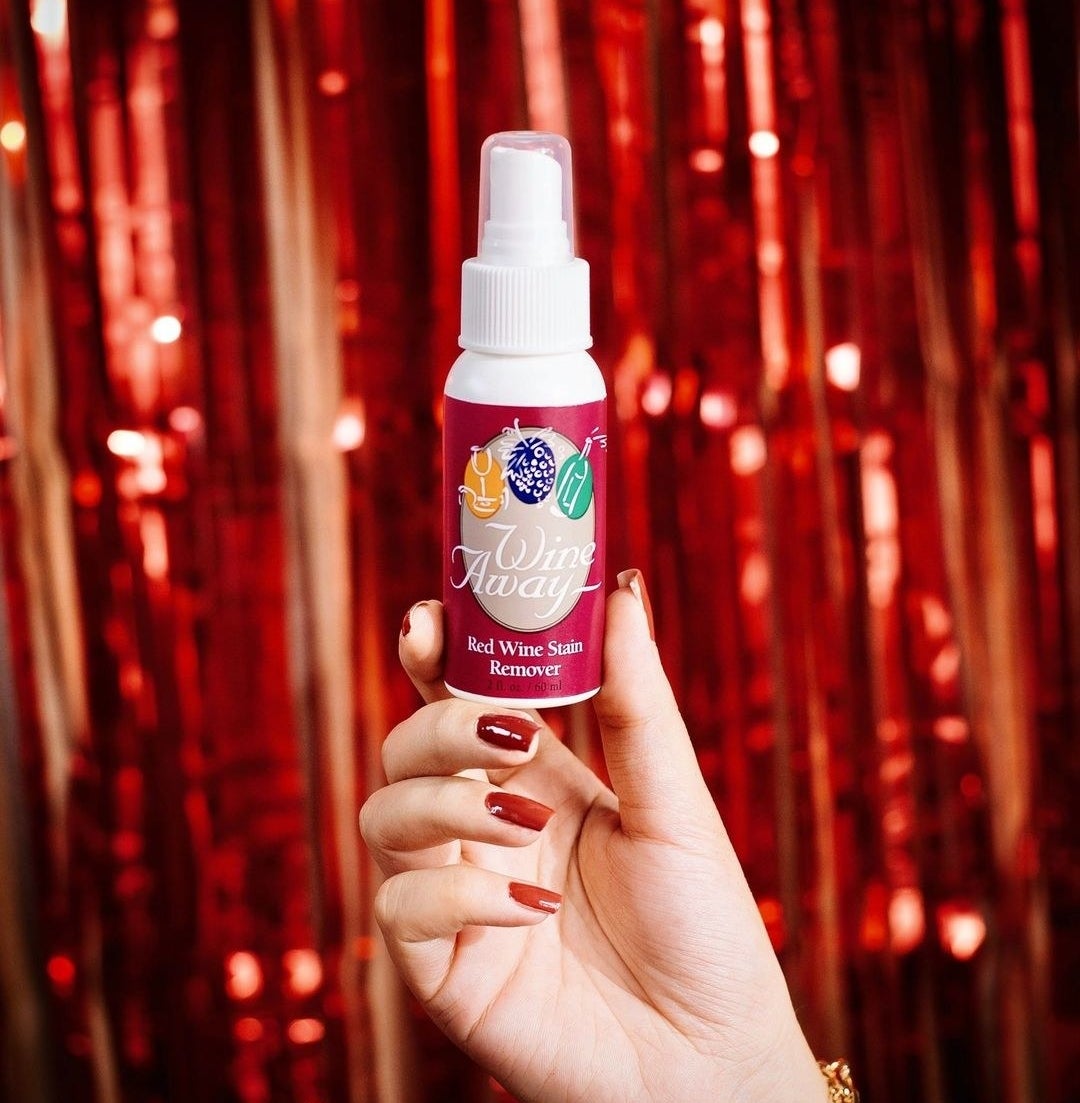 a person holding up a bottle of the red wine stain remover