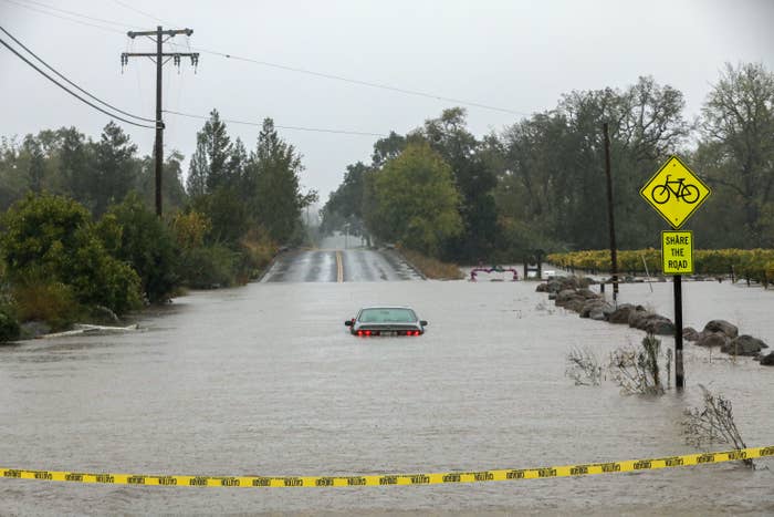 A flooded country road with flood waters reaching halfway up a sign post