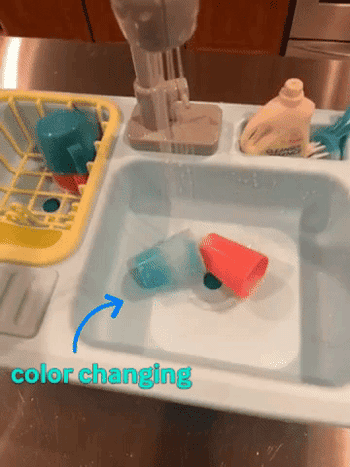 Reviewer showing the toy sink with the blue cup changing color under the running water