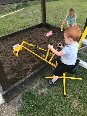 Reviewer's child sitting on the excavator and scooping sand in the sand pit