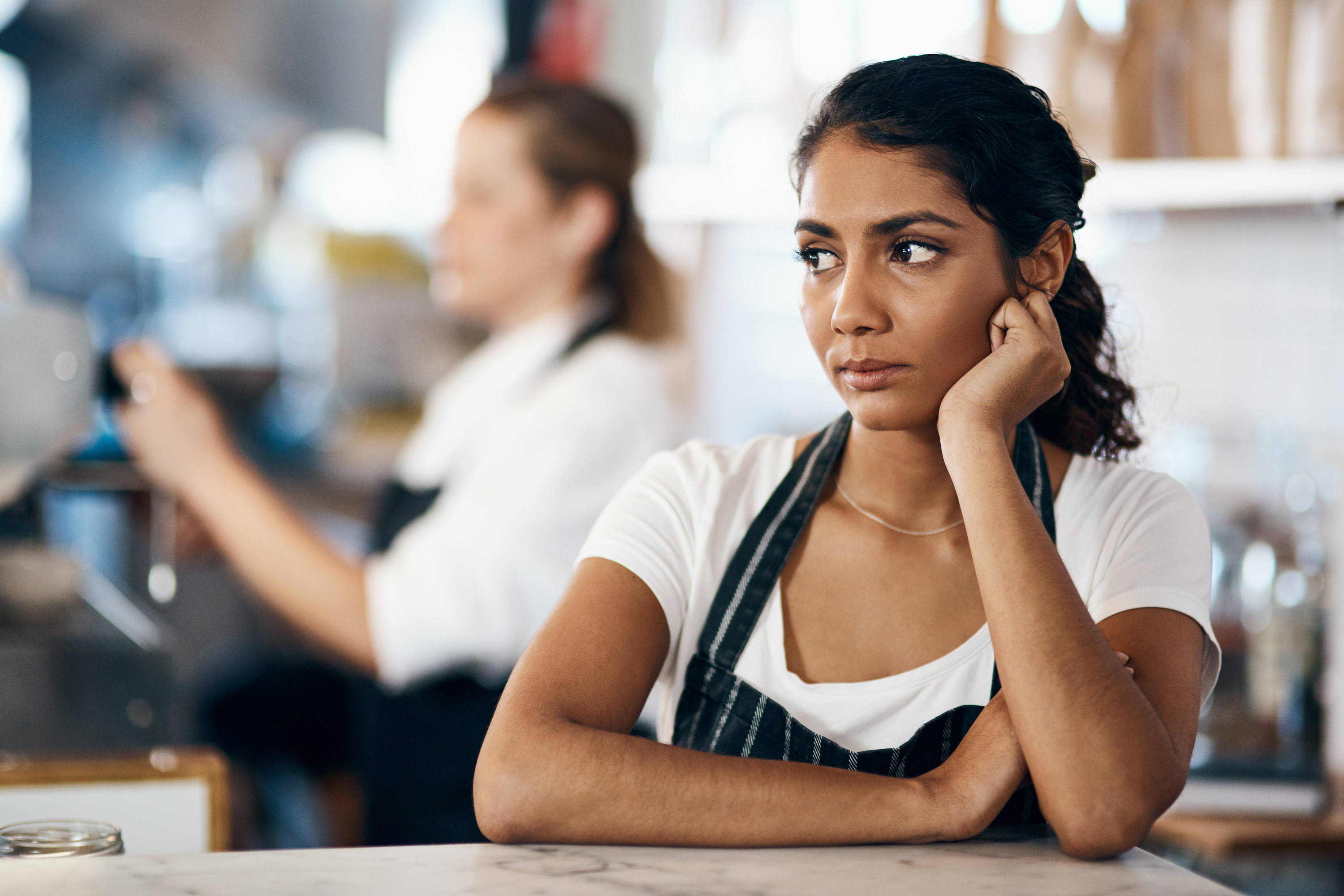 Barista at a cafe looking annoyed while behind the counter