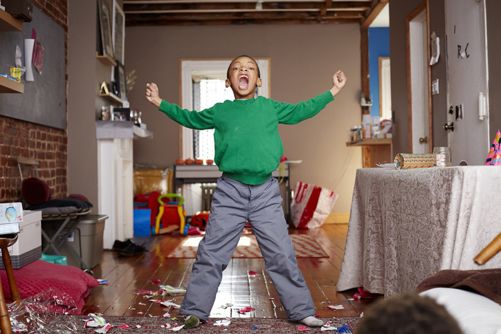 boy shouting with his arms out in living room