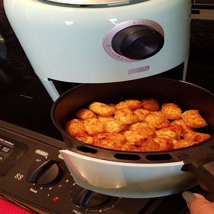 A reviewer shows cooked tater tots after using the blue air fryer