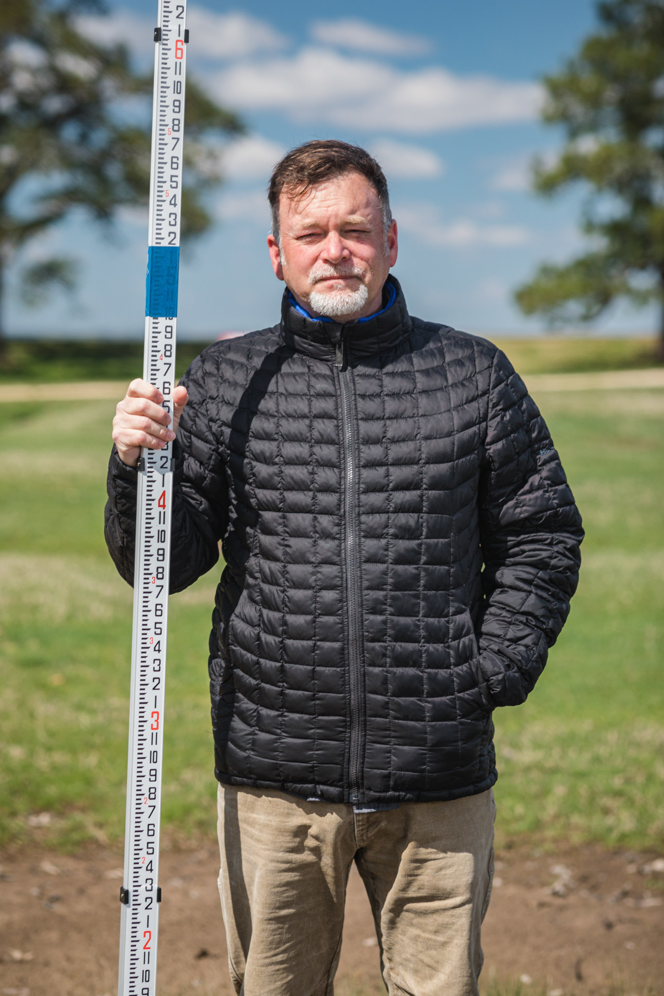 A man in a Black puffer jacket holding a depthmarker.