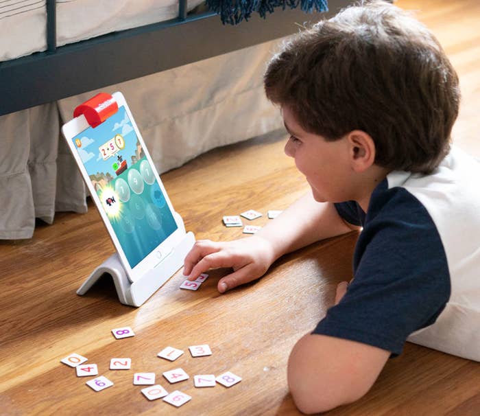 Young child plays with tablet and numbered cards