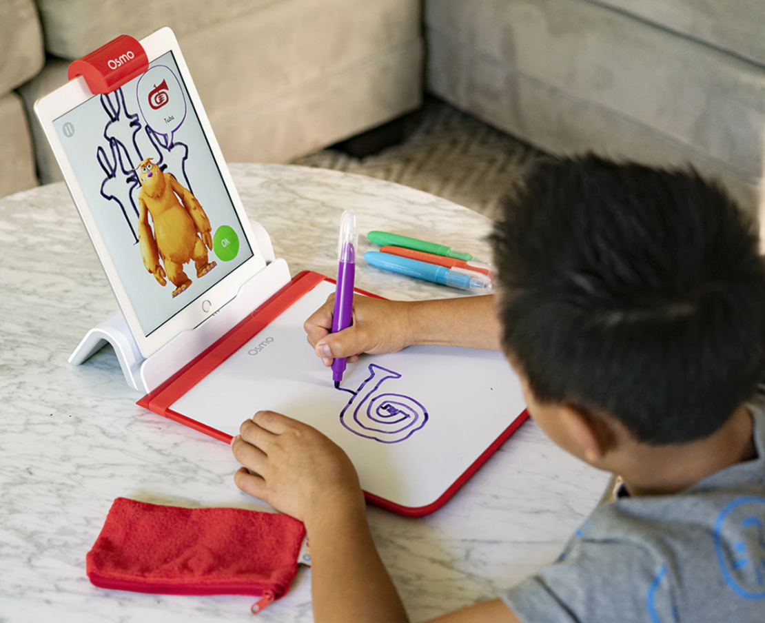 Young child drawing while playing with tablet
