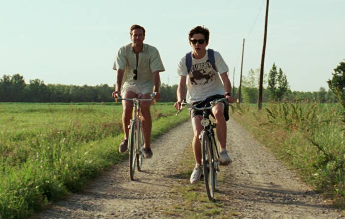 Armie and Timothee ride bikes on a dirt road in a screenshot from the movie