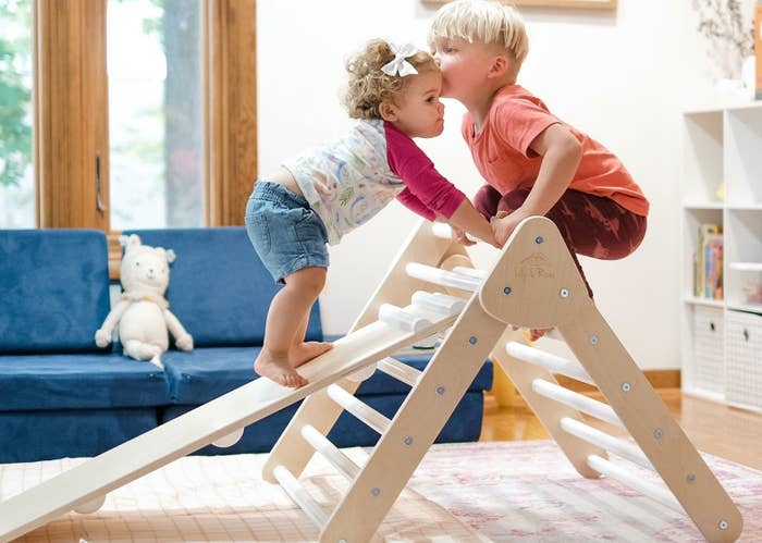 Two kids climbing the wooden triangle and ladder set