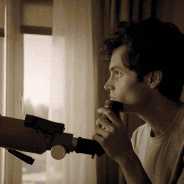 Joe (Penn Badgley) looks through a telescope