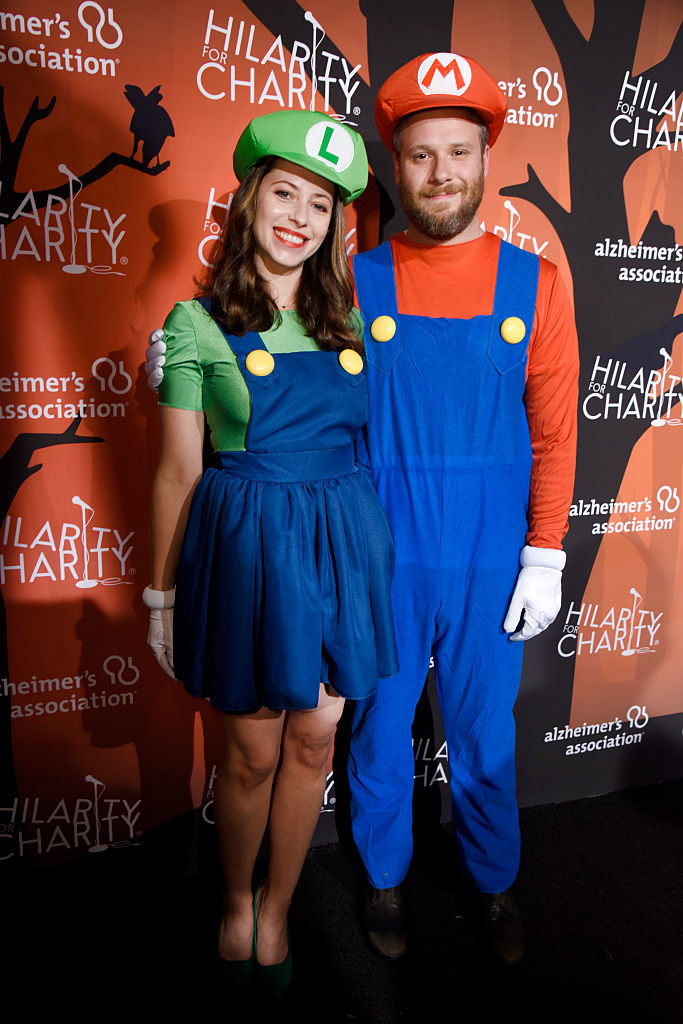 Seth Rogen wears a brightly colored long sleeve shirt under overalls and Lauren Miller wears a short jumper skirt over a brightly colored t-shirt