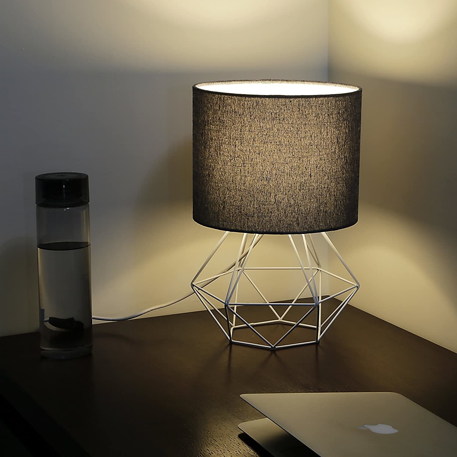 A lamp with a black shade and a geometric, white stand