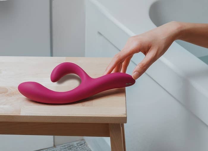 Model reaching for pink Nova 2 vibrator from tub