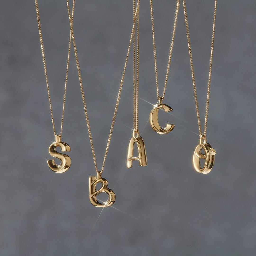 Five necklaces with different letter pendants hanging from them