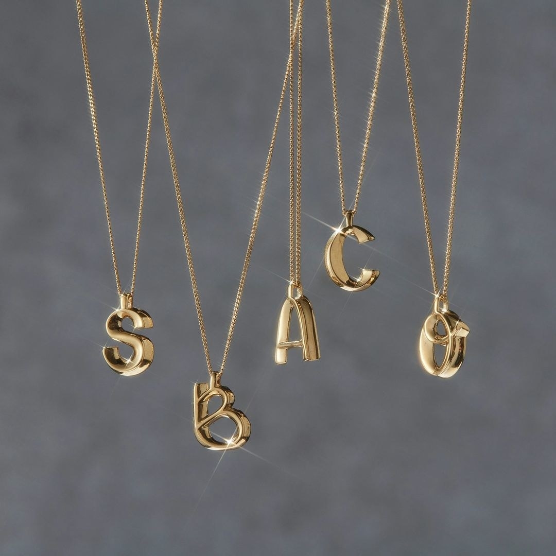 Five necklaces with different letter pendants hanging from them