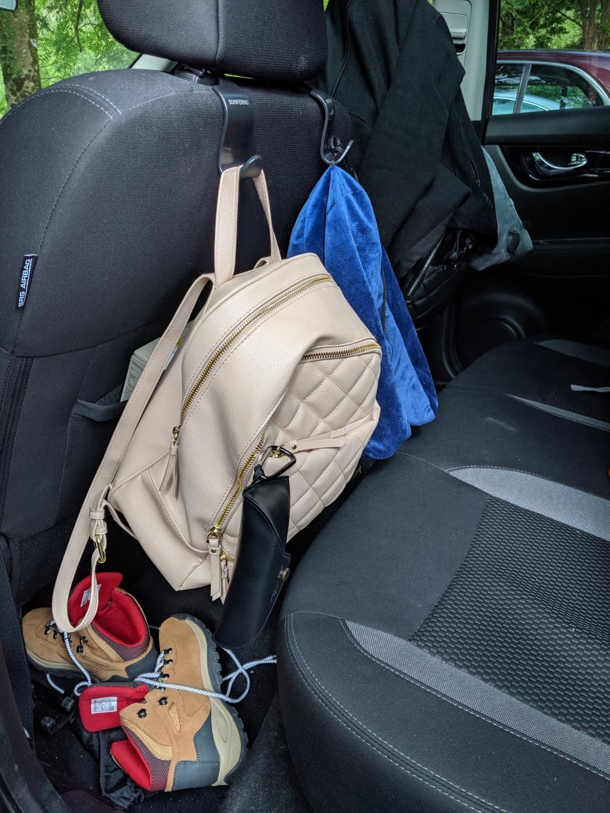 black hooks holding up backpacks and hiking gear behind car seat