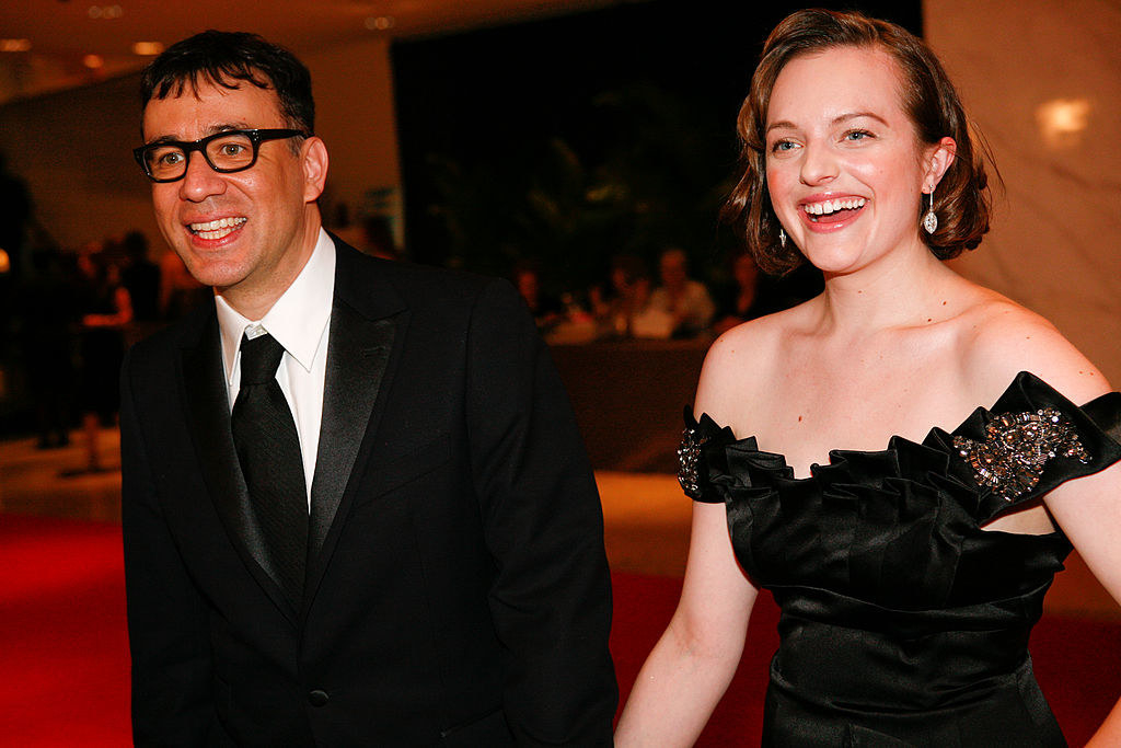 Fred Armisen in a suit and tie and Elisabeth Moss in an off-the-shoulder dress