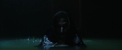 A dimly lit creepy nun rises out of the water