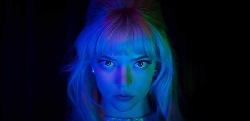Anya Taylor Joy stares into the camera ominously as a multicolored light glows on her face