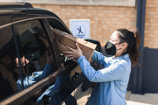 A worker hands a customer a package at Curbside Pickup.