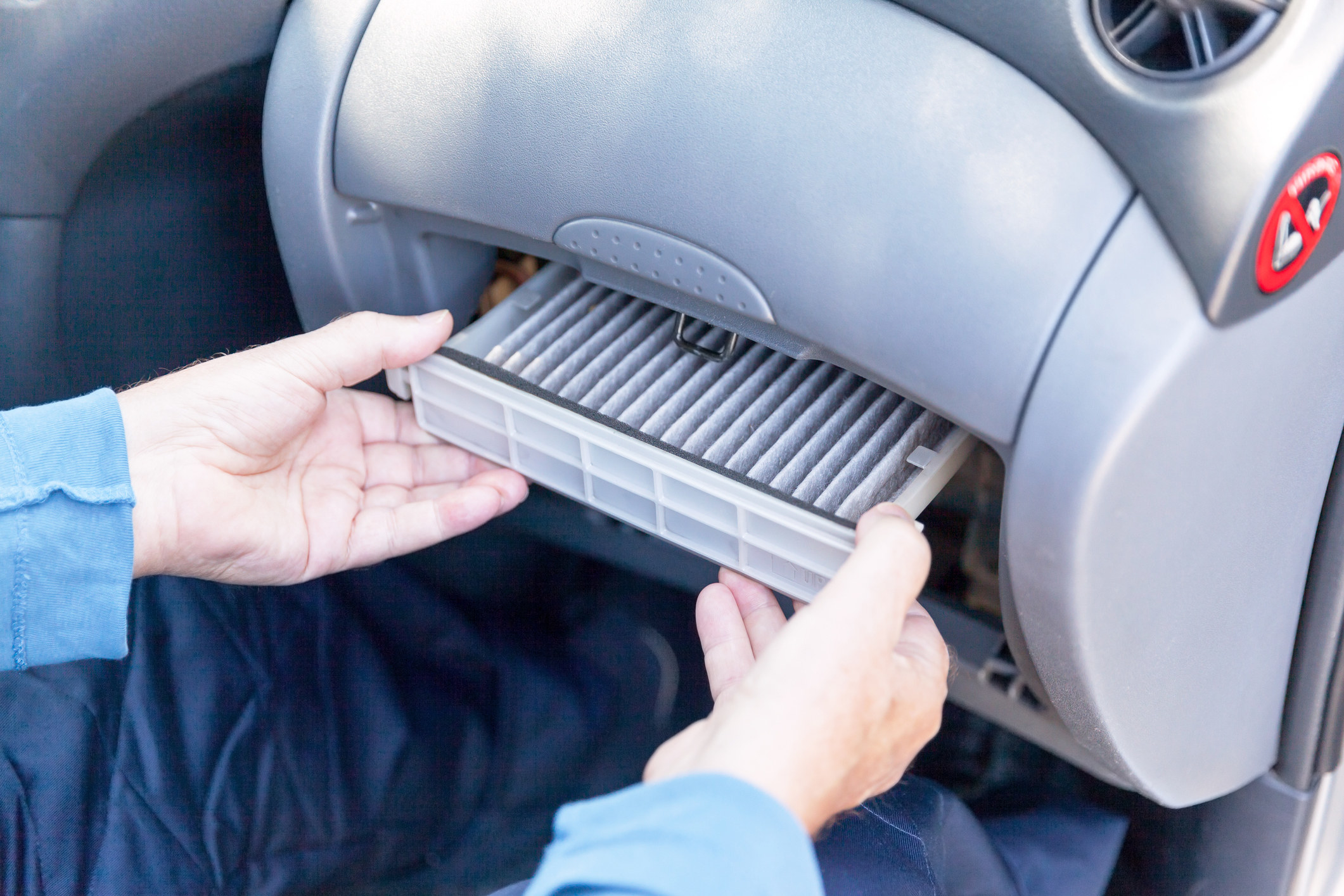 A person opens the air filter in a car.