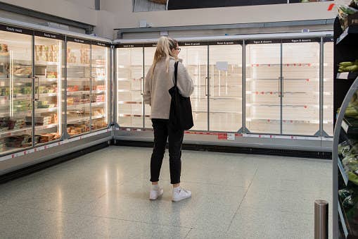 A woman stares at empty shelves.