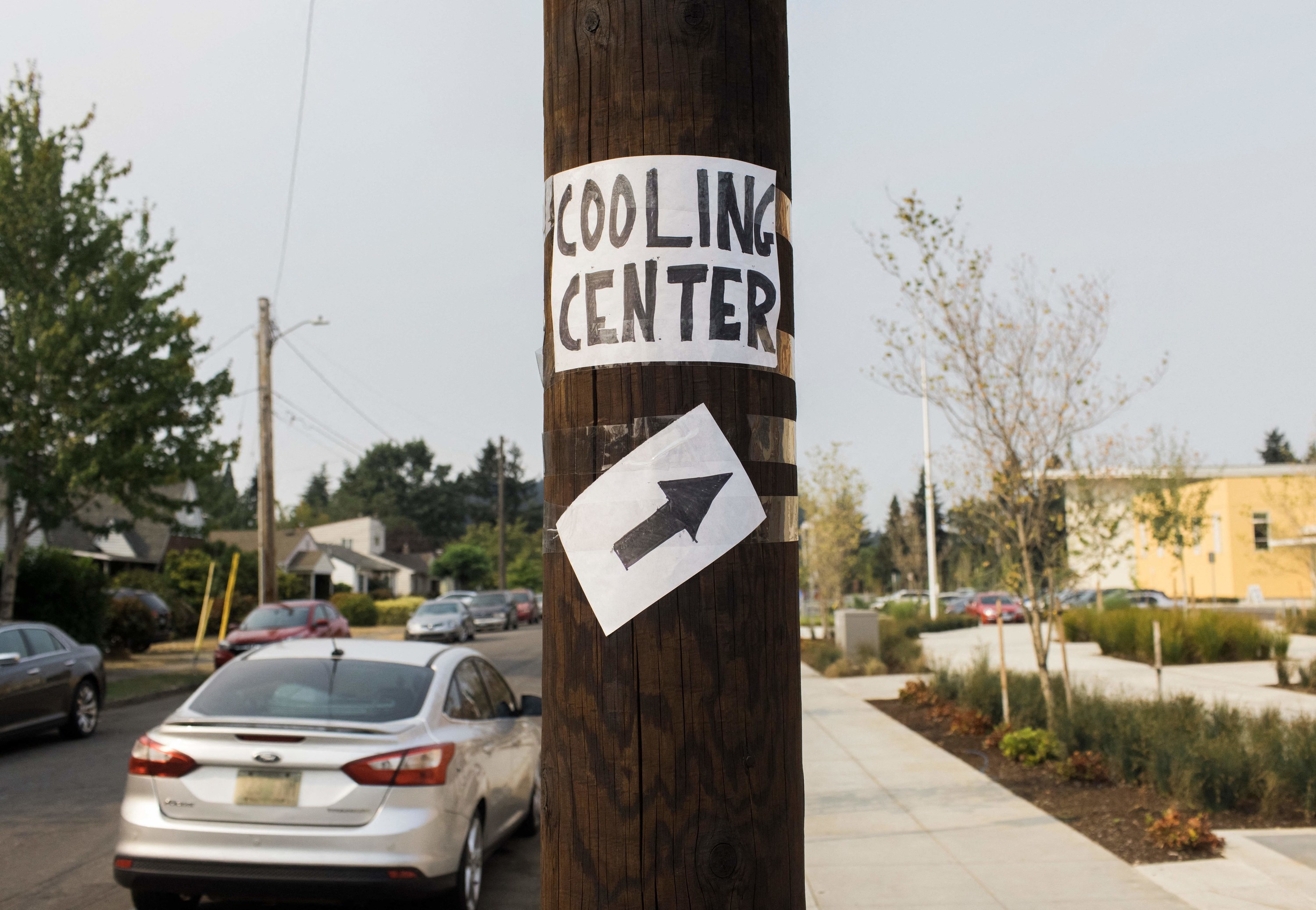 A street sign on a pole with an arrow pointing to a &quot;Cooling Center&quot;