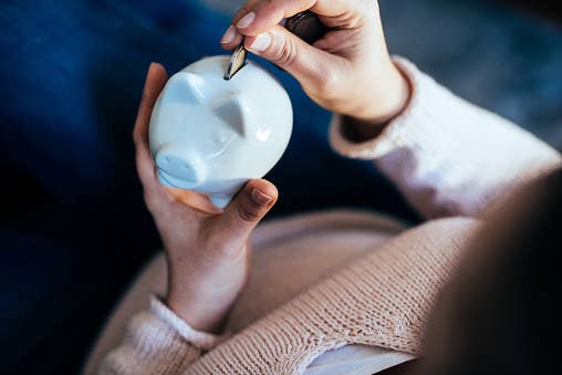 A person puts a coin in a piggy bank.