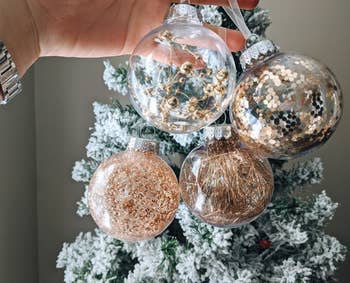 Reviewer photo of four of the gold ball ornaments in front of a Christmas tree