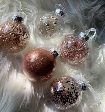 Reviewer photo of five of the pink ball ornaments on a white shag rug