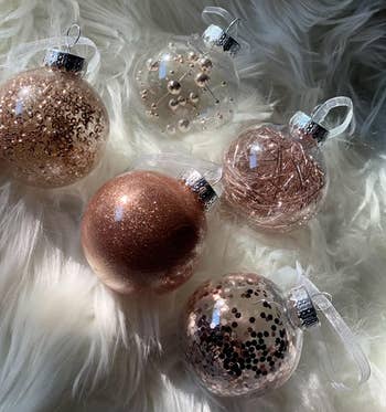 Reviewer photo of five of the pink ball ornaments on a white shag rug