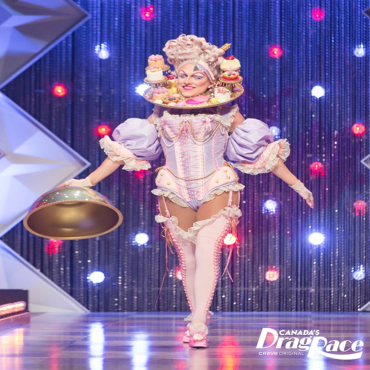 drag queen on the runway in victorian corset with her head on a platter