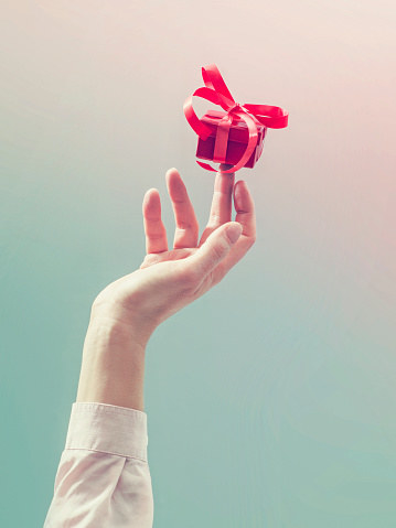 A hand holding up a small box on one finger.