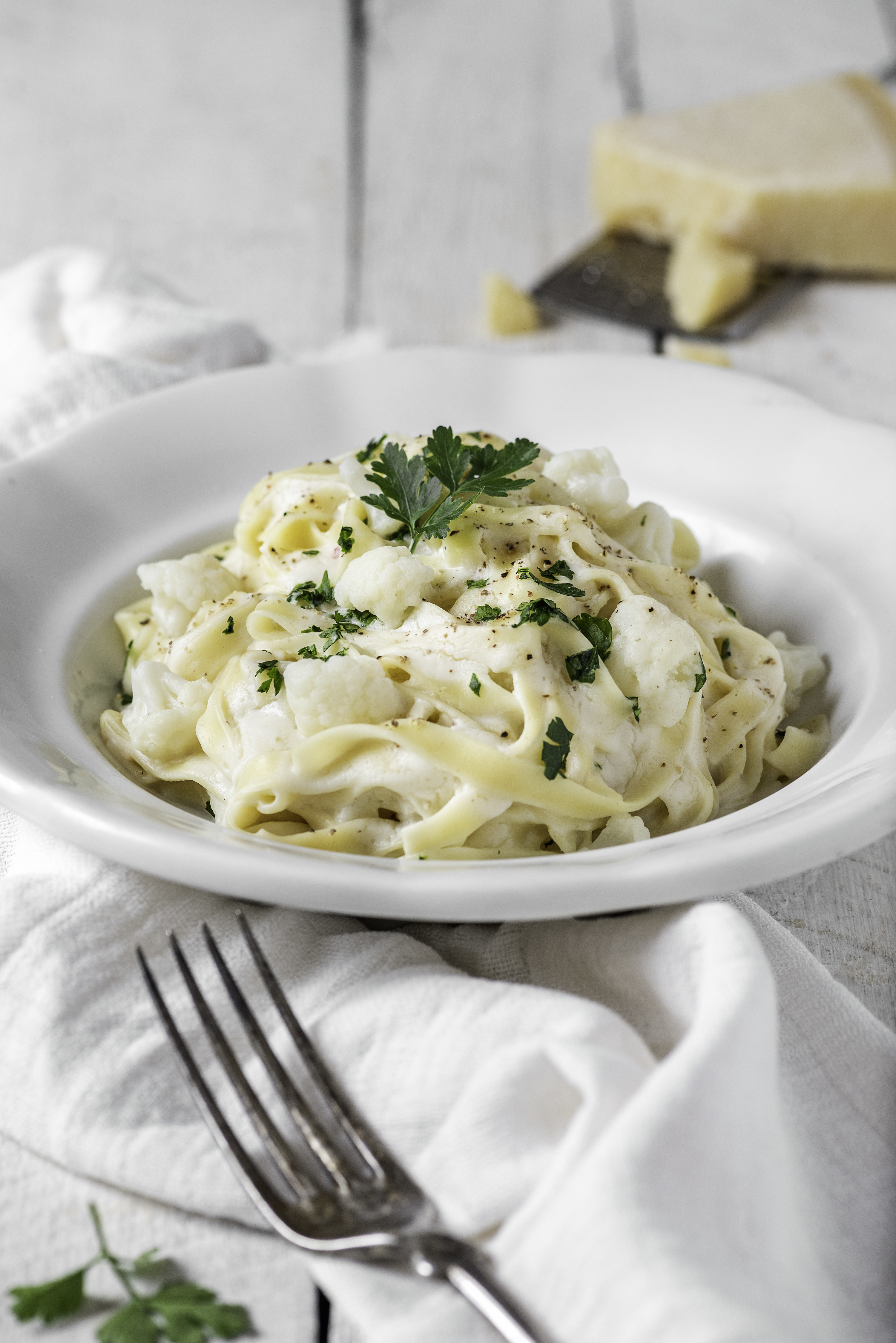 Bowl of creamy pasta with parsley liberally sprinkled on top.