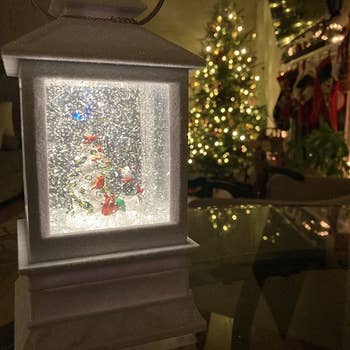 reviewer photo of the lit and snowing lantern in front of a Christmas tree