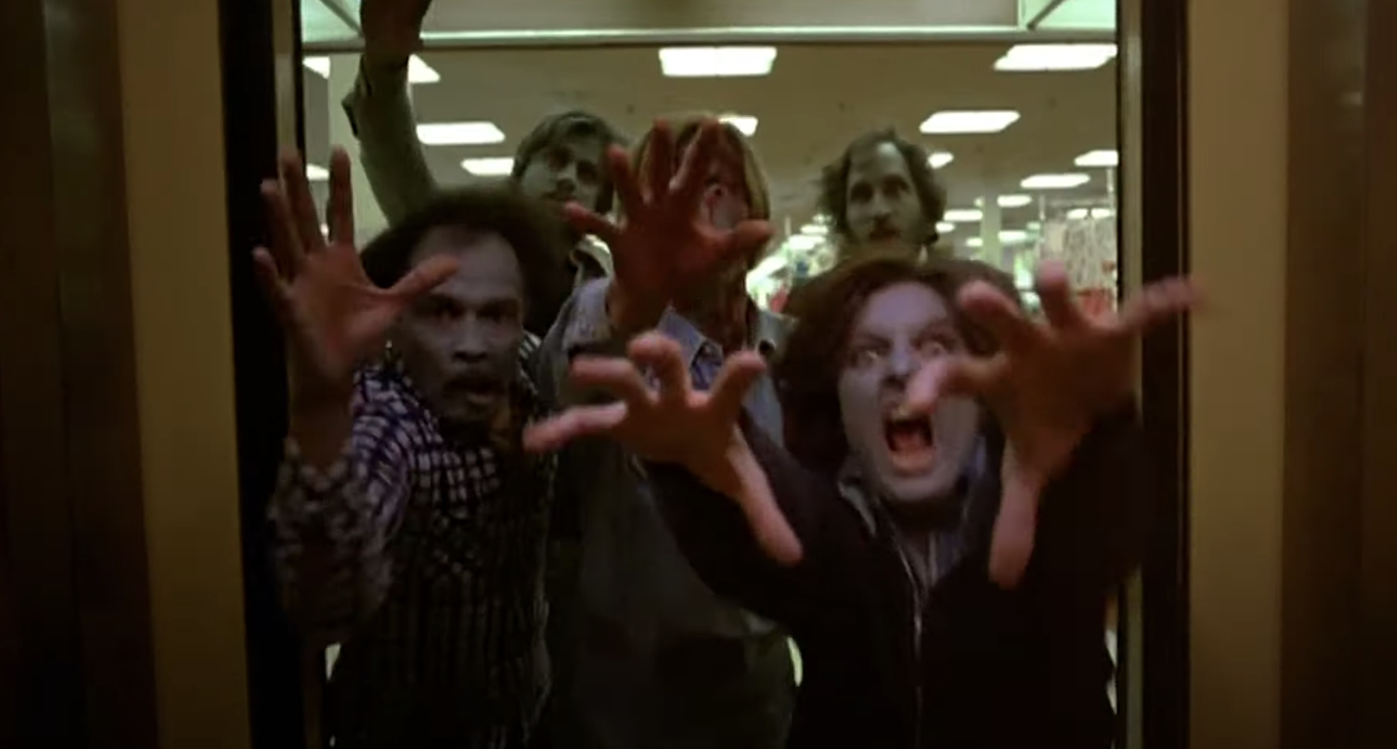 A group of zombies lunge forward with outstretched hands