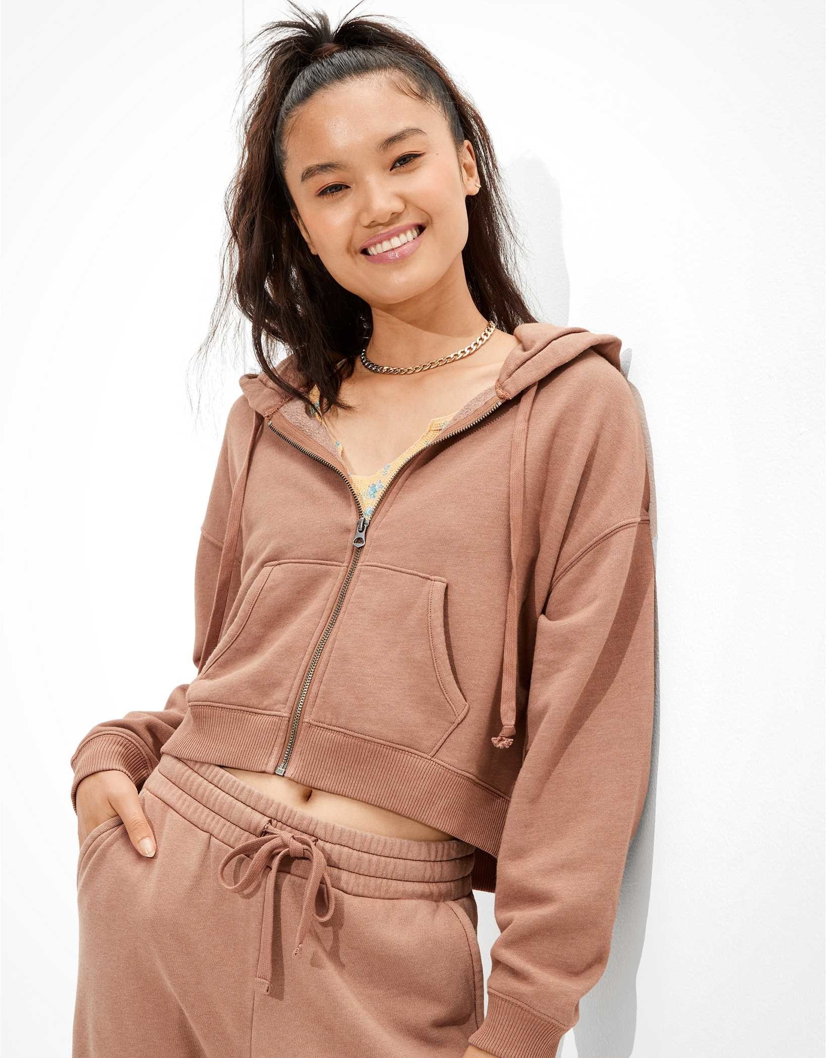 A model wearing a brown cropped zip up hoodie